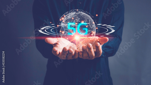 Human hand holding earth globe holographic technology, hand holding network using 5G technology with virtual screen icons on a black background, Technology Internet 5G global network concept.