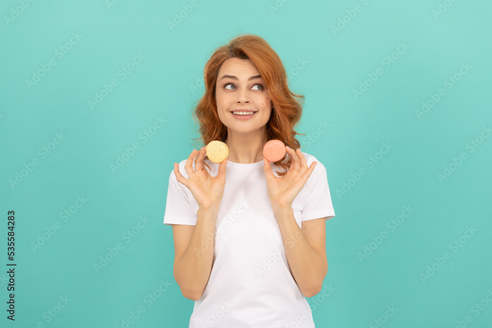 Fototapeta premium glad girl hold sweet macaron french cookie on blue background