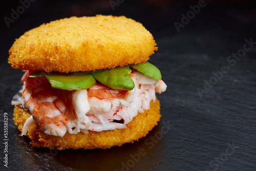 Pan-Asian cuisine concept. Japanese sushi burger made from rice bread, crab meat, avokado and wasabi sauce. Serving on wooden board. copy space photo