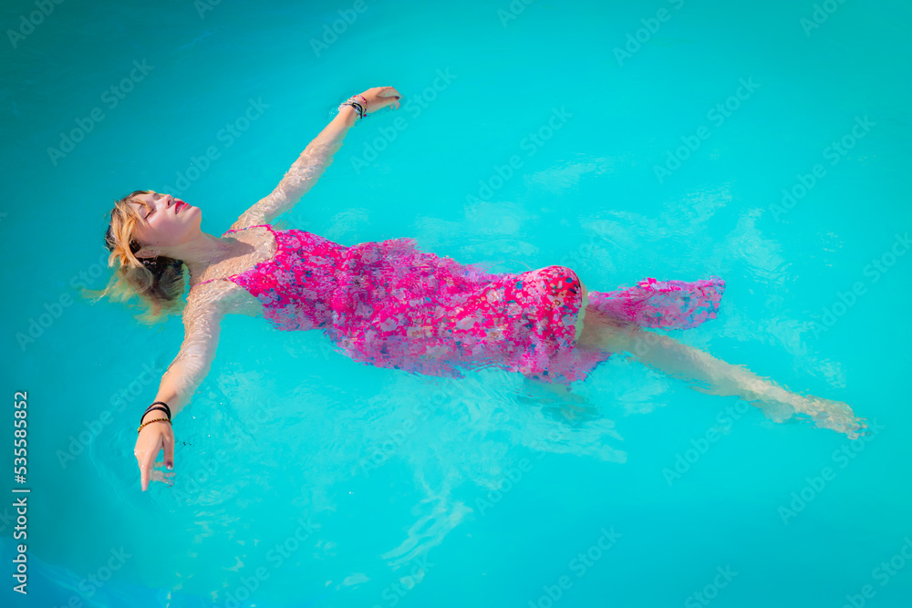 Jeune femme se baignant avec sa robe dans la piscine