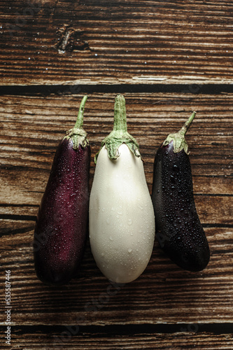 
Fresh purple and white eggplant with water drops on wooden background