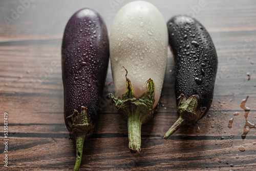 
Fresh purple and white eggplant with water drops on wooden background