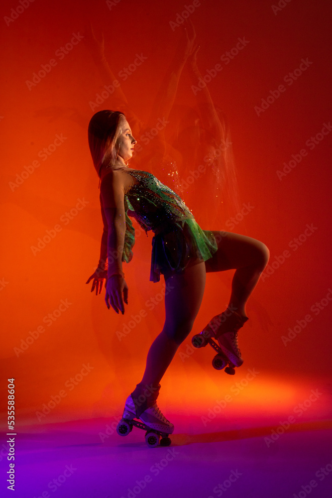 Dancing young mixed race girl enjoying moving in colorful neon studio light. Long exposure. woman dancing on roller skates, figure skating