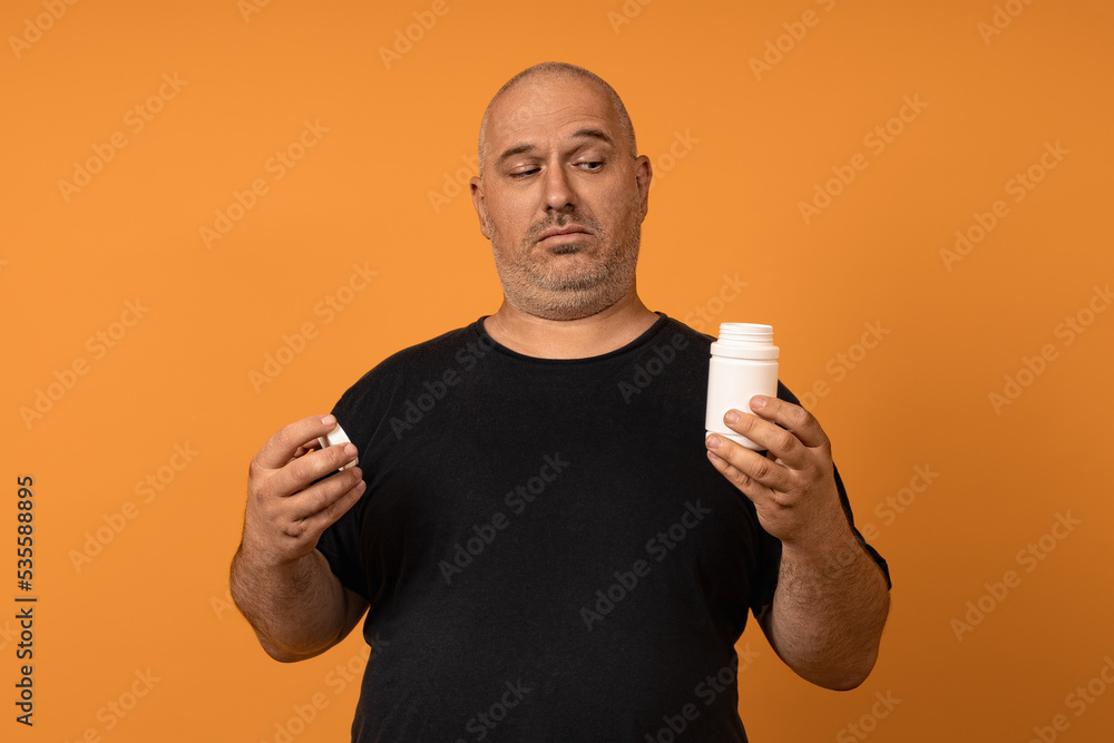 the man glances furtively at the open vial of his pills. medication concept the man glances furtively at the open vial of his pills. medication concept