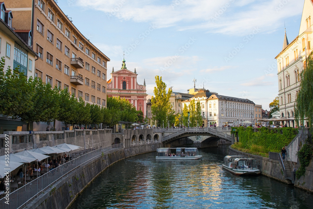 The Triple Bridge or Tromostovje over the Ljubljanici River in central Ljubljana, with the Franciscan Church of the Annunciation in the background. An historic group of 3 bridges made from granite, li