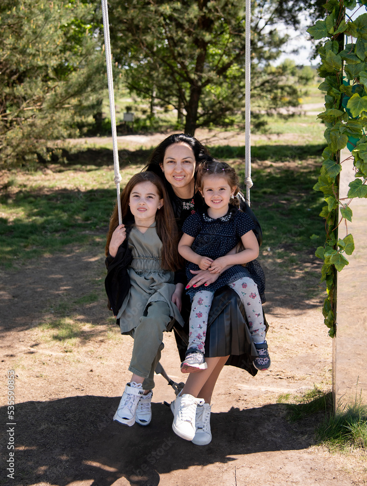 mother and daughters on swing in green park