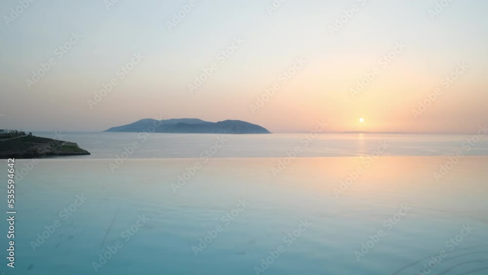 Beautiful big swimming pool overlooking the Aegean Sea at the Pathos lounge bar and Restaurant in Ios Greece while the sun is setting Beautiful big swimming pool overlooking the Aegean Sea at the Pathos lounge bar and Restaurant in Ios Greece while the sun is setting