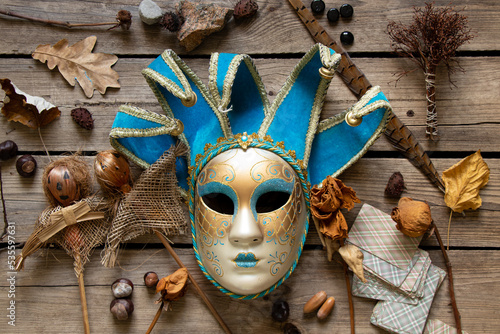 The Venetian mask lies on a wooden table with feather cards and voodoo dolls and shamanic items, mystery