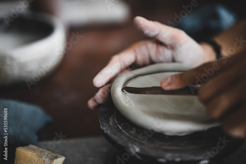 View of male hands works with clay makes future ceramic plate, ceramic artist makes classes of hand building in modern pottery workshop, creative people handcrafted design