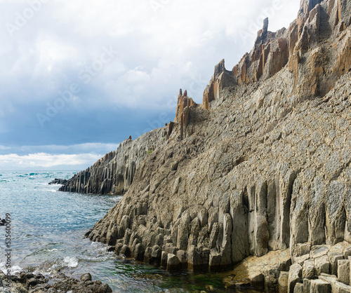 ocean shore with rocks of columnar basalt, Cape Stolbchaty on Kunashir Island photo