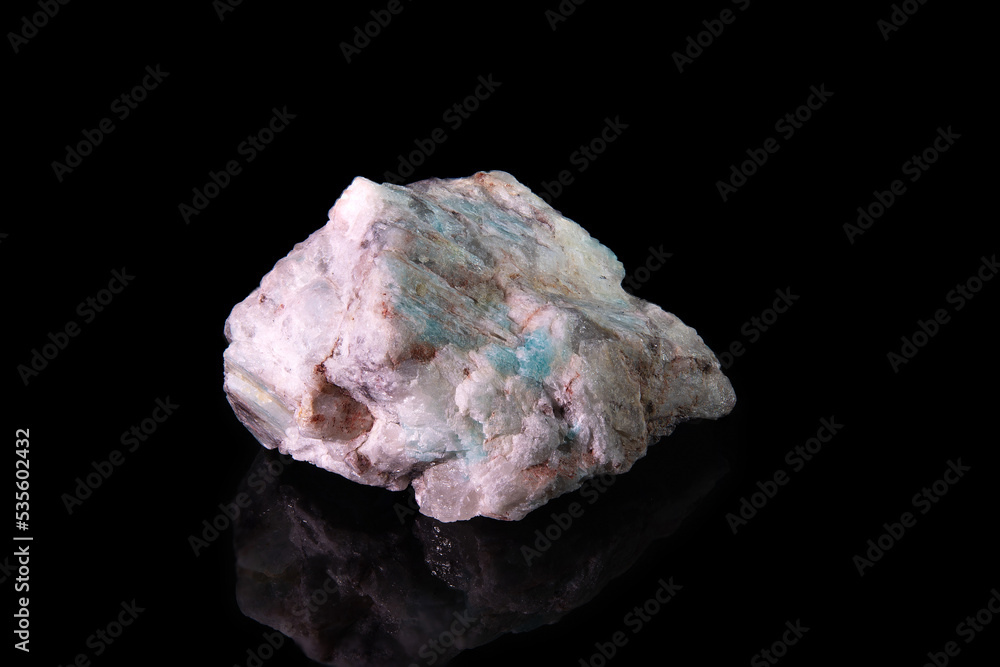 A fragment of the mineral amazonite is whitish in color with black and green blotches A fragment of the mineral amazonite is whitish in color with black and green blotches