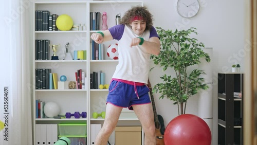Goofy guy in 80s style sportswear performing awkward comic dance in room alone photo