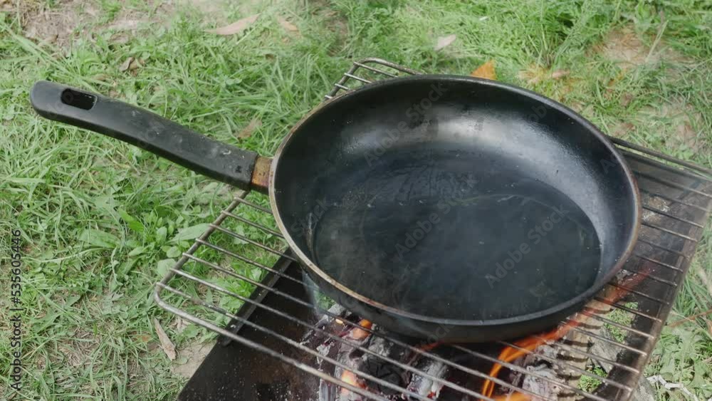 frying pan with boiling oil on the grate for grilling in nature frying pan with boiling oil on the grate for grilling in nature