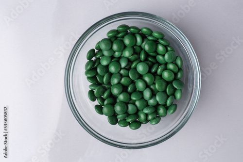 Green candy coated chocolate button sprinkles in a bowl on marble - M&Ms, Smarties, sprinkles