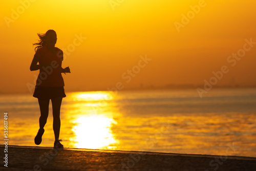 Silhouette of young sportive woman are running on the river. Healthy running and outdoor exercise