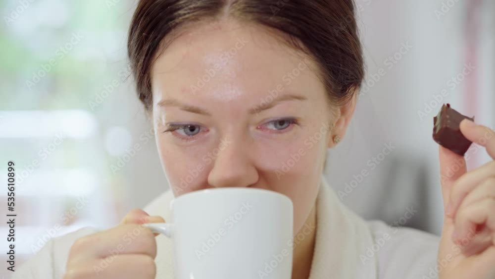 Fragrant hot morning coffe. The woman enjoys a delicious leisurely breakfast in a hotel. Unhealthy diet with high carbohydrates. Portrait of a girl drinking a warm tea from a white mug at home. Fragrant hot morning coffe. The woman enjoys a delicious leisurely breakfast in a hotel. Unhealthy diet with high carbohydrates. Portrait of a girl drinking a warm tea from a white mug at home.