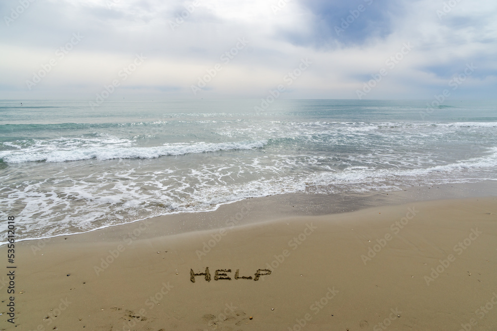 Words Written in the sand. The word HELP written in the sand with the ocean in the background.
