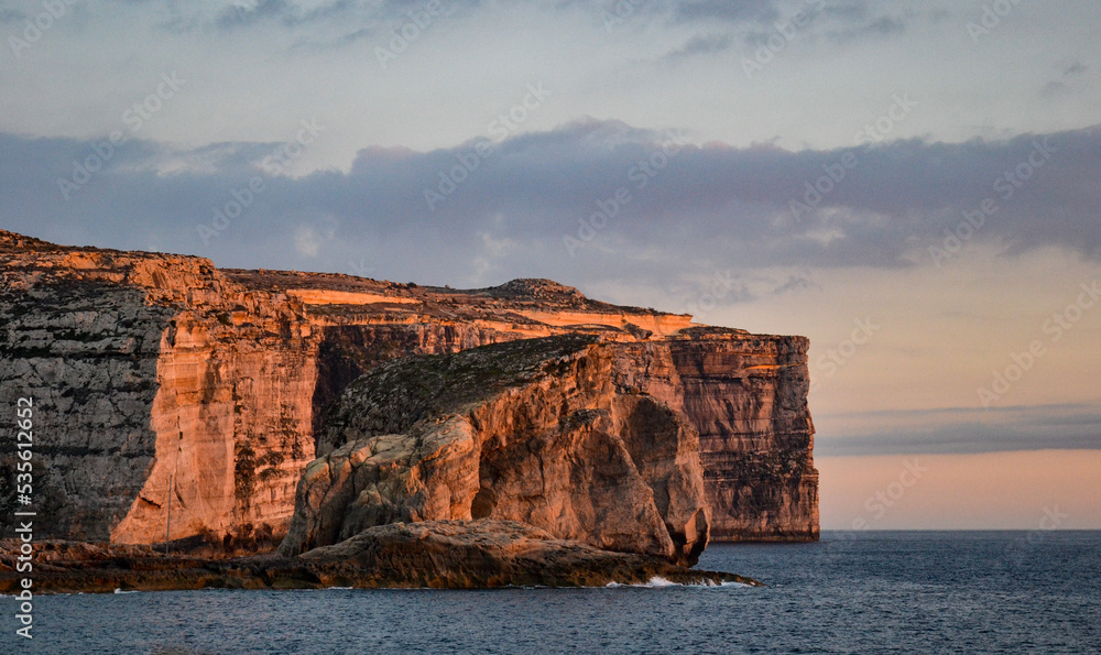Coucher de soleil sur la mer et les célèbres falaises de The Stone Crocodile et Fungus Rock, sur l'île de Gozo, Malte