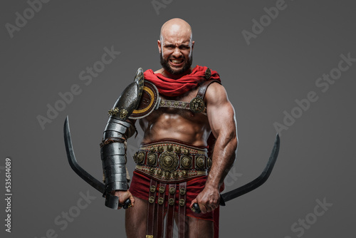 Shot of furious praetorian warrior with two swords dressed in armor and red cape.