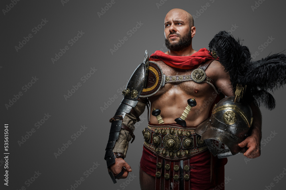 Shot of serious roman gladiator with naked torso and plumed helmet isolated on grey background.