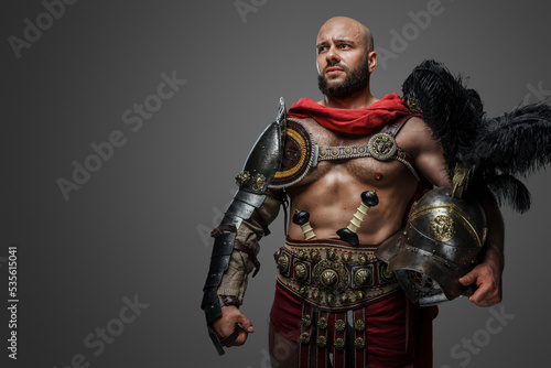 Shot of serious roman gladiator with naked torso and plumed helmet isolated on grey background.