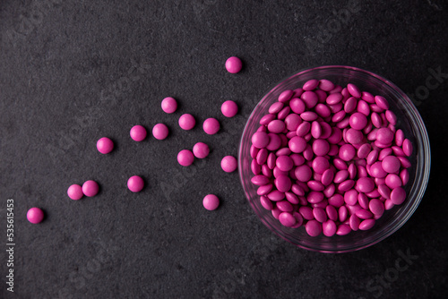 Fotografija Pink candy coated chocolate button sprinkles in a bowl on dark slate - M&Ms, Sma