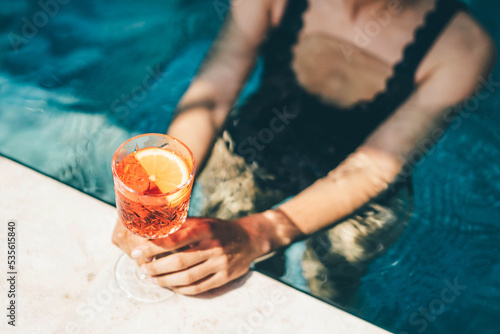 Obraz na plátně Young woman relaxation on poolside with cold and fresh Spritz cocktail