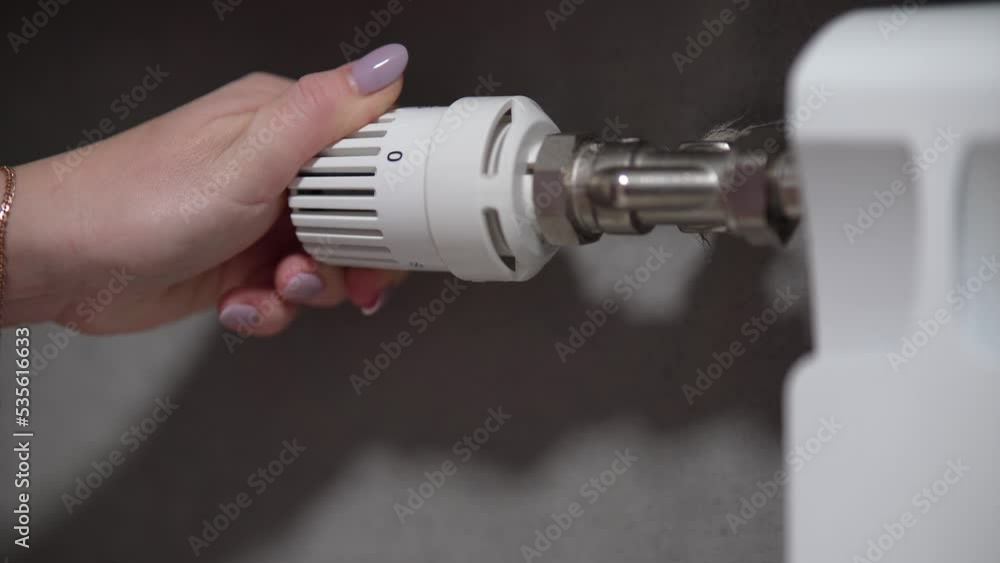 Hand adjusting temperature on heating radiator thermostat, saving energy by adjusting heating thermostat. Hand adjusting temperature on heating radiator thermostat, saving energy by adjusting heating thermostat.