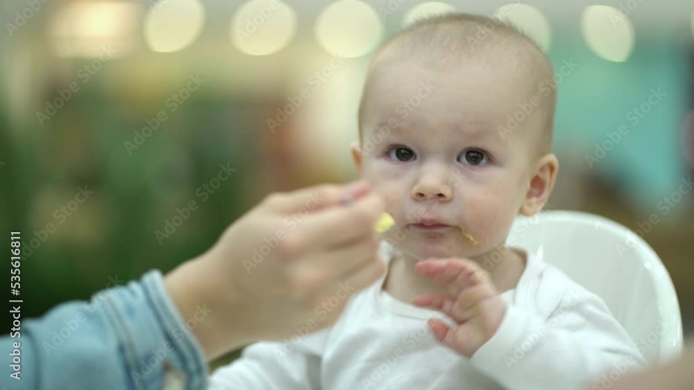 mother feeding son with baby food mother feeding son with baby food