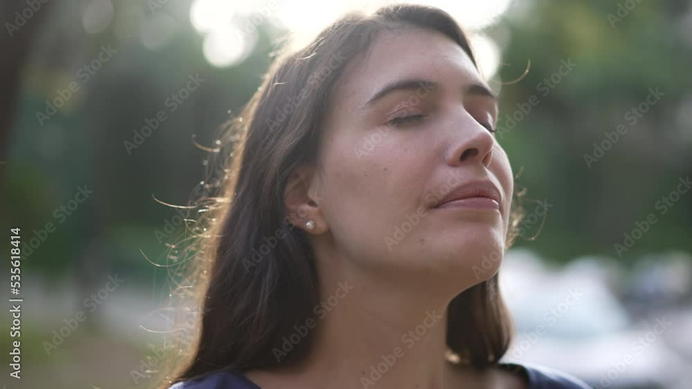 Meditative young woman closing eyes in contemplation standing outdoors in nature Meditative young woman closing eyes in contemplation standing outdoors in nature