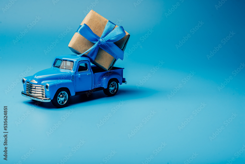 Fototapeta premium The toy car is loaded with a gift. minimalism in blue
