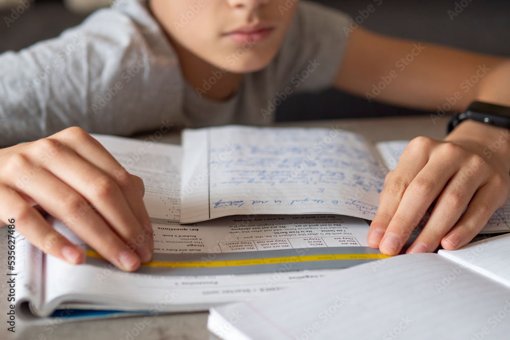 Kid affected by dyslexia doing homework, writing, reading notebook task using colorful overlay strip. Education, learning disability, reading difficulties concept Kid affected by dyslexia doing homework, writing, reading notebook task using colorful overlay strip. Education, learning disability, reading difficulties concept