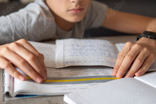 Kid affected by dyslexia doing homework, writing, reading notebook task using colorful overlay strip. Education, learning disability, reading difficulties concept photo