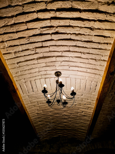 Looking up to white brick ceiling with old chandelier photo