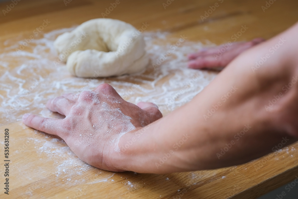 Close up of hands in flour lean on the table next to dough Close up of hands in flour lean on the table next to dough