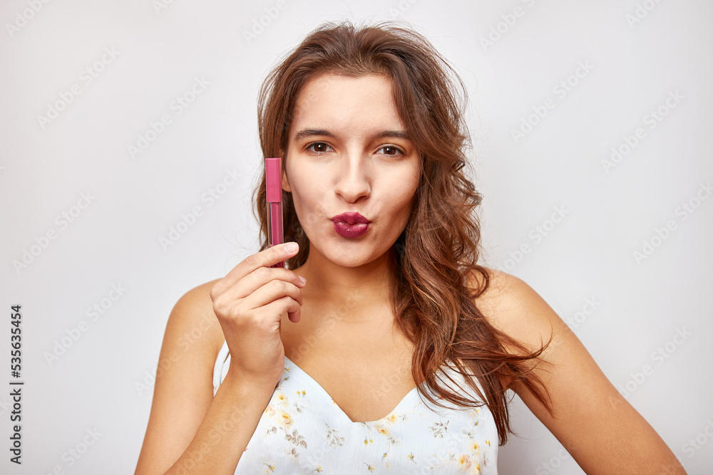 A beautiful girl holds pink lipstick in her hands. Selection and use of cosmetics. A beautiful girl holds pink lipstick in her hands. Selection and use of cosmetics.