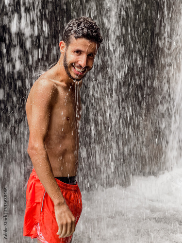 Man standing under a waterfall photo