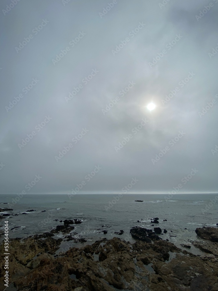 Grey cloudy coastal landscape on the shore of a quiet rocky beach at autumn