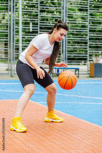 Young athletic woman is training to play basketball on modern outdoor basketball court. Happy woman © Olha Tsiplyar