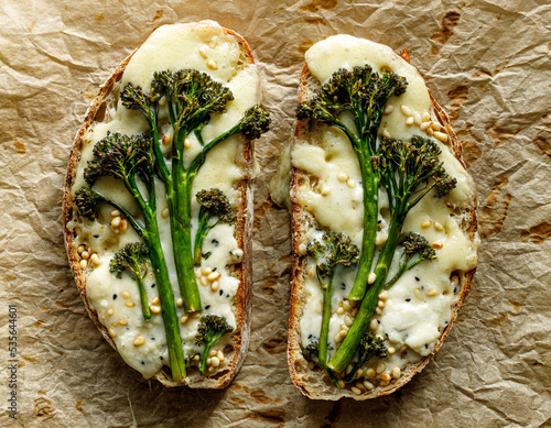Grilled sandwiches, toasts with addition of baby broccoli, cheese and pine nuts  on parchment paper, top view