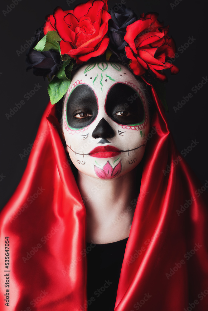 attractive woman with sugar skull make-up, red dress, flowers on her head, posing with confidence and expressive look attractive woman with sugar skull make-up, red dress, flowers on her head, posing with confidence and expressive look