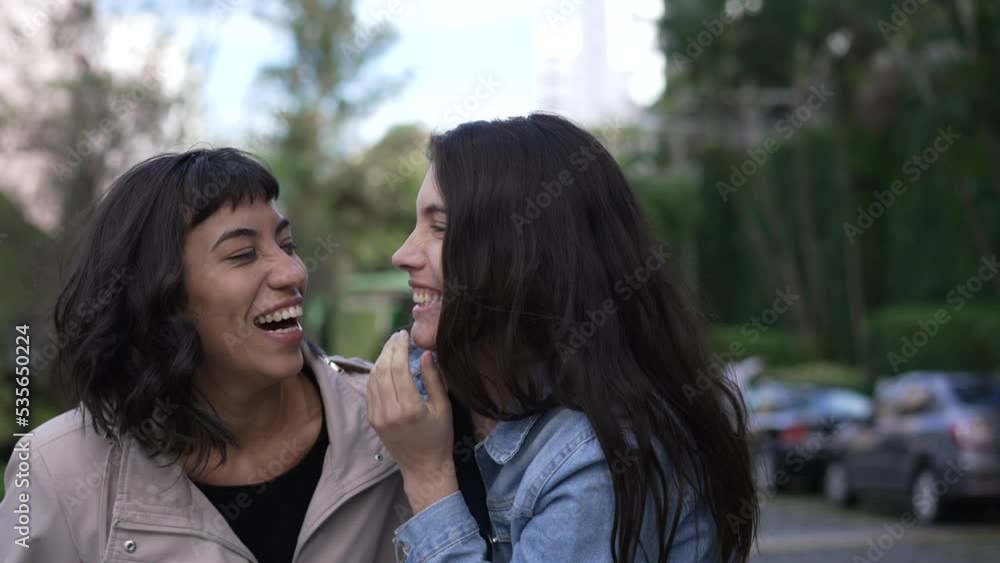 Two female friends laughing and smiling together pointing at funny reaction Two female friends laughing and smiling together pointing at funny reaction