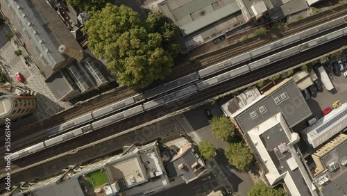 Train track aerial top down trains passing in London sunny tree lined streets. 