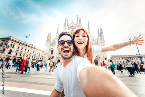 Happy couple taking selfie in front of Duomo cathedral in Milan, Lombardia - Two tourists having fun on romantic summer vacation in Italy - Holidays and traveling lifestyle concept