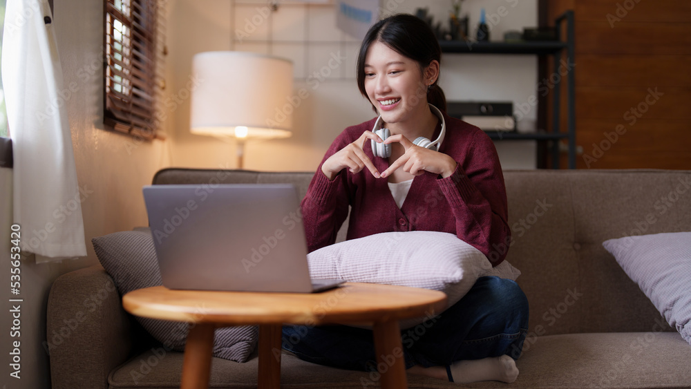 Young asian woman sitting on couch looking at laptop in cozy living room at home. Lifestyle concept Young asian woman sitting on couch looking at laptop in cozy living room at home. Lifestyle concept