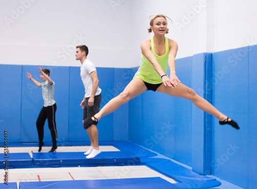 Athletic young woman training jumping movements in indoor trampolines center © JackF