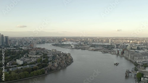 Following the river thames at sunset, city skyline and boats moving. O2 Greenwich Peninsula. 