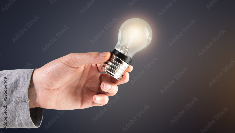 The hand holds a glowing light bulb. The hand holds a glowing light bulb.