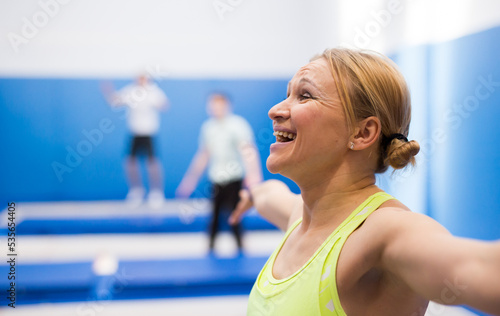 Closeup portrait of emotional young athletic woman exercising acrobatic jump elements in trampoline center .. © JackF