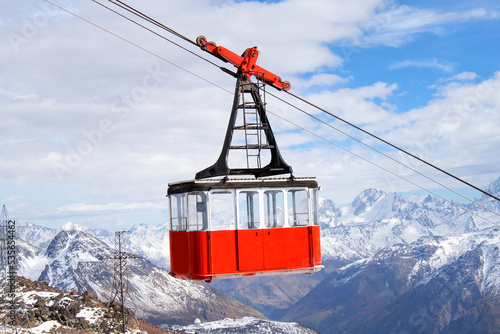 Red retro cable car cabin against the backdrop of snow-capped mountains photo